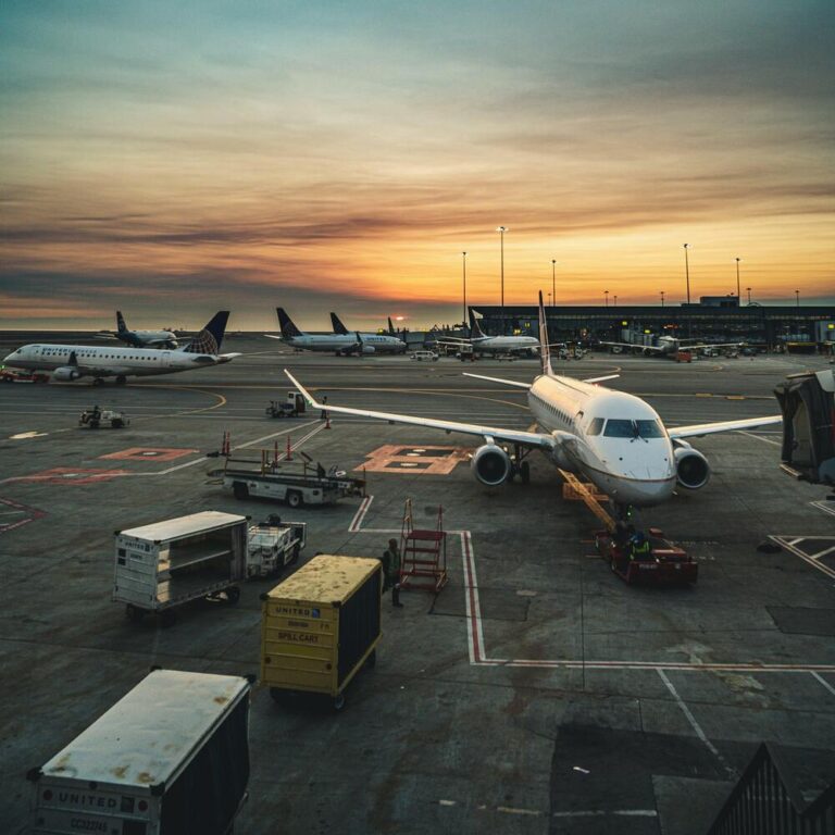 A runway scene at sunset showcases several parked airplanes, with ground equipment featuring quality pre-owned GSE and terminal buildings in the background.
